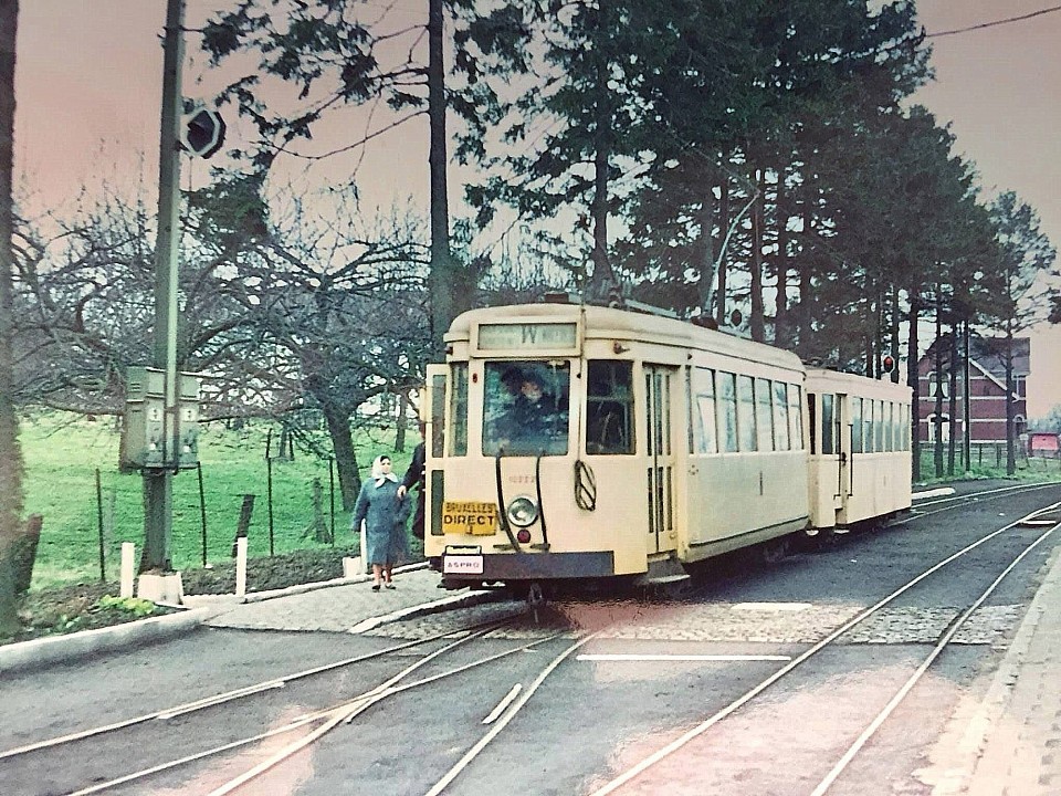 Un tram arrive de Chapelle et s’arrête au niveau du bâtiment des voyageurs de la gare de Lasne Il s'agit d'un cliché pris par l'anglais Jack Wyse, en mars 1964, à la station de Lasne