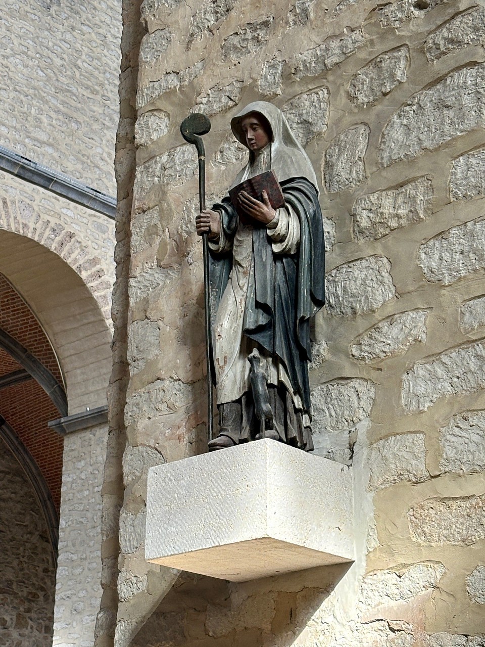 Photo de Sainte-Gertrude prise en la Collégiale de Nivelles @RZ Dans l'art chrétien, Sainte Gertrude est souvent représentée avec : - La Crosse : Un symbole de son rôle d'abbesse, représentant son autorité et son leadership spirituel. - Le Livre : Symbolisant sa sagesse et son engagement envers l'enseignement et la prière. - Les Souris : Parfois, elle est accompagnée de souris, en référence à sa protection contre ces rongeurs, symbole de prospérité pour les agriculteurs.